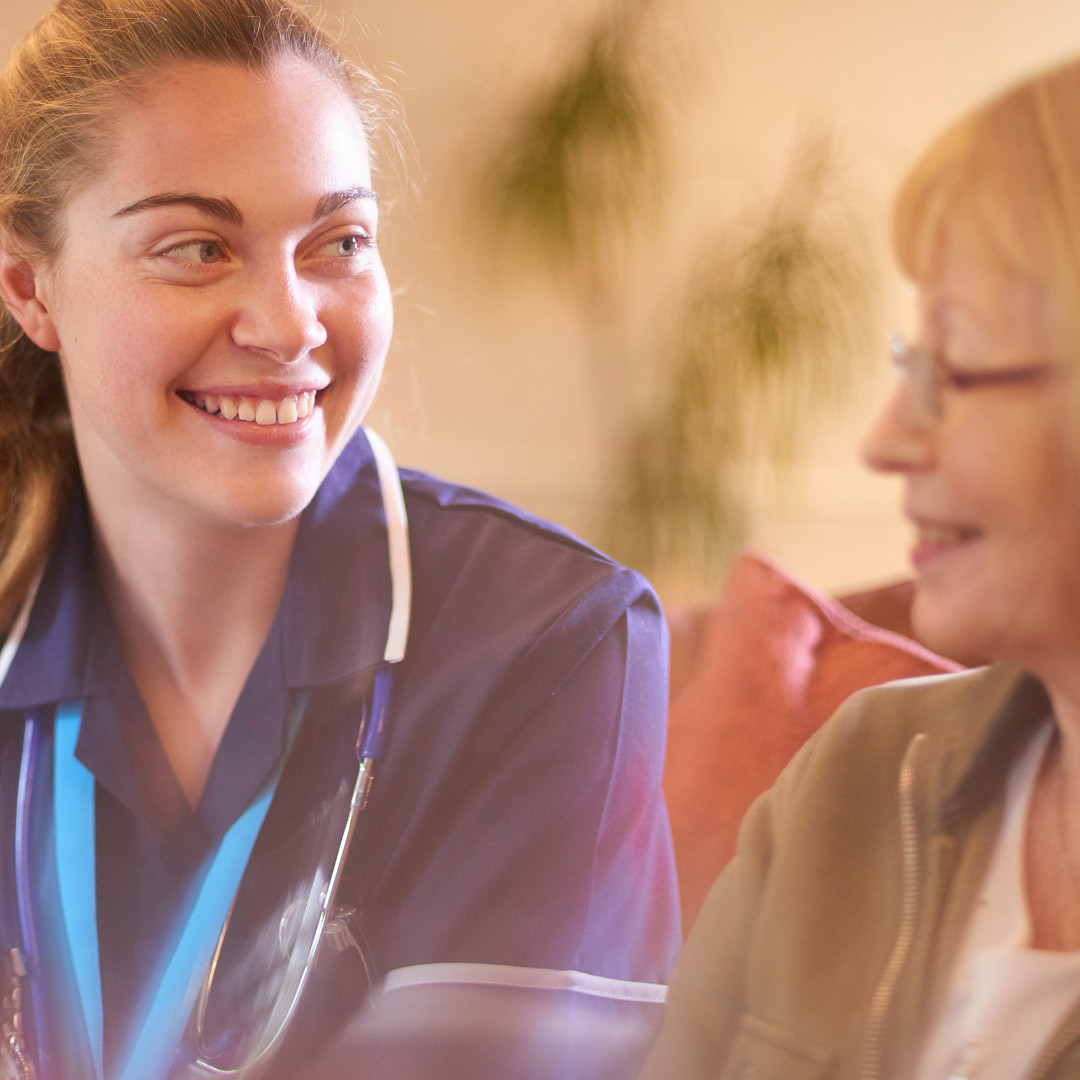 carer looking and smiling at elderly lady slightly out of shot
