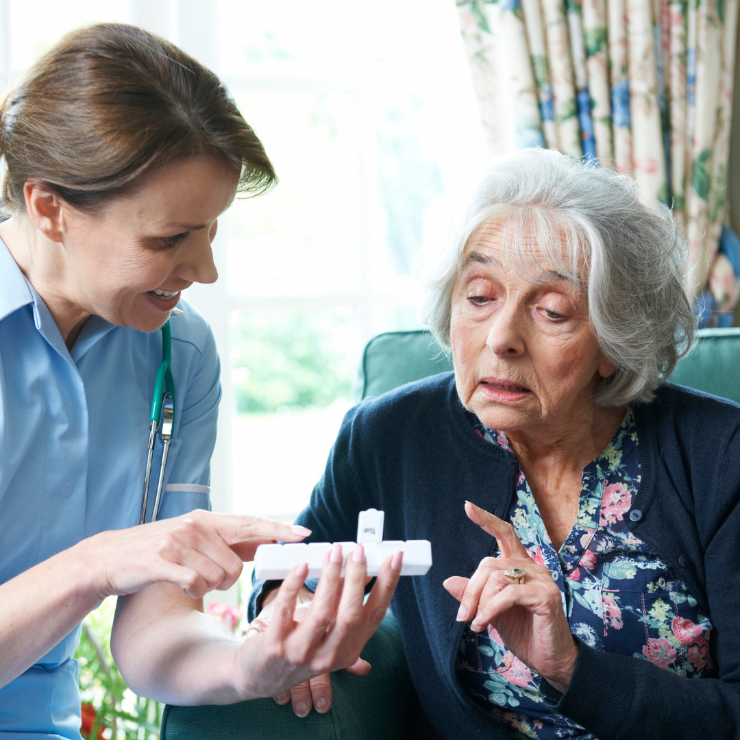 Elderly lady and carer looking a medication packet together while having a conversation